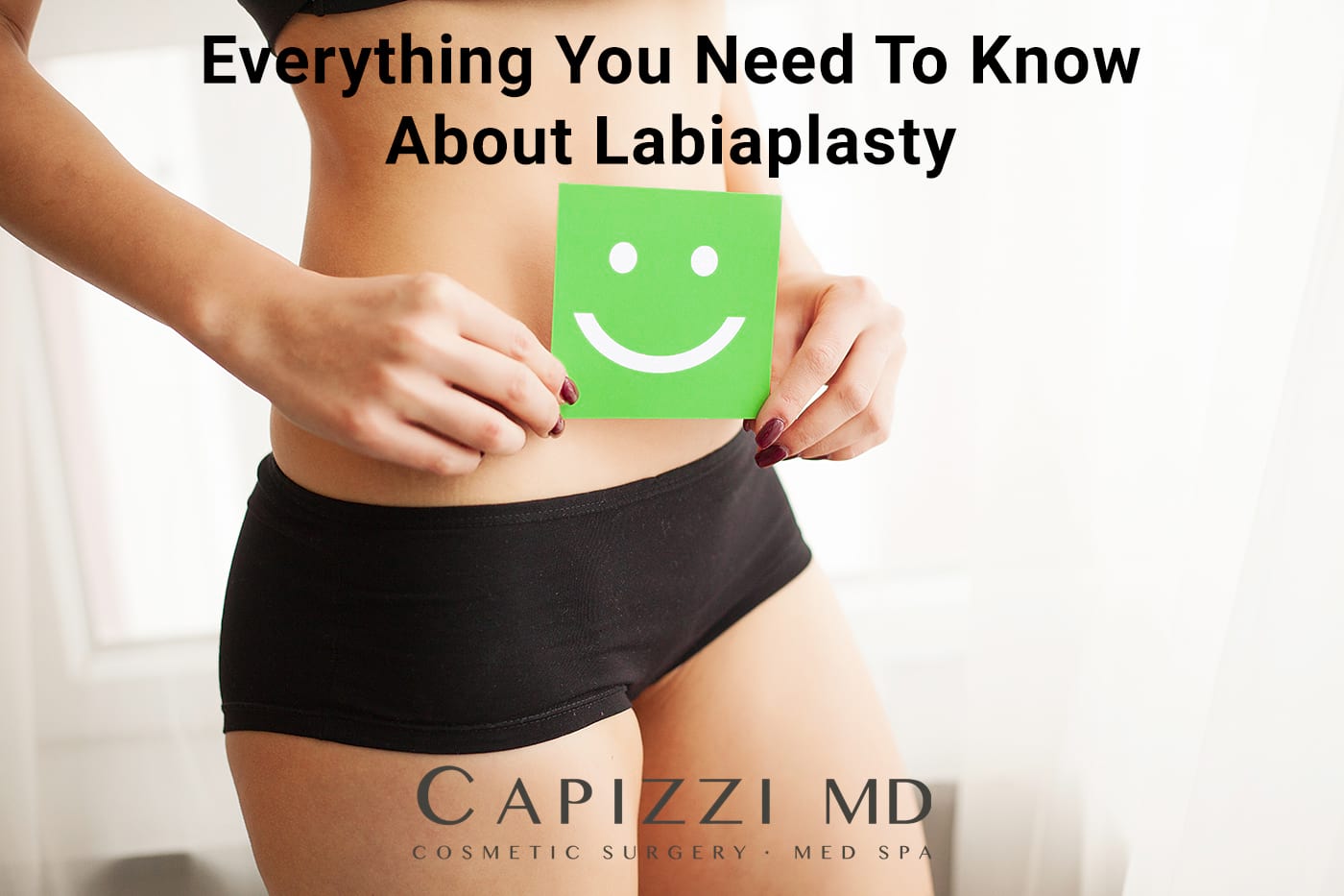Women in black shorts holding green smiley face with text "Everything You Need To Know About Labiaplasty" and Capizzi MD logo