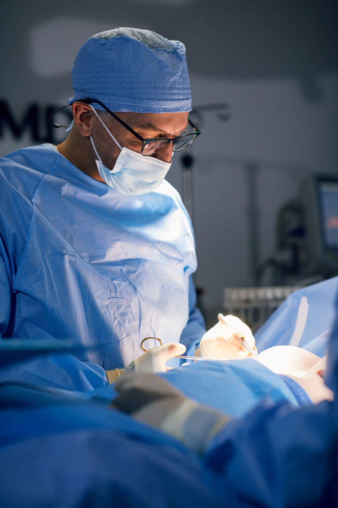 Dr. Peter Capizzi board certified plastic surgeon in operating room completing a breast augmentation
